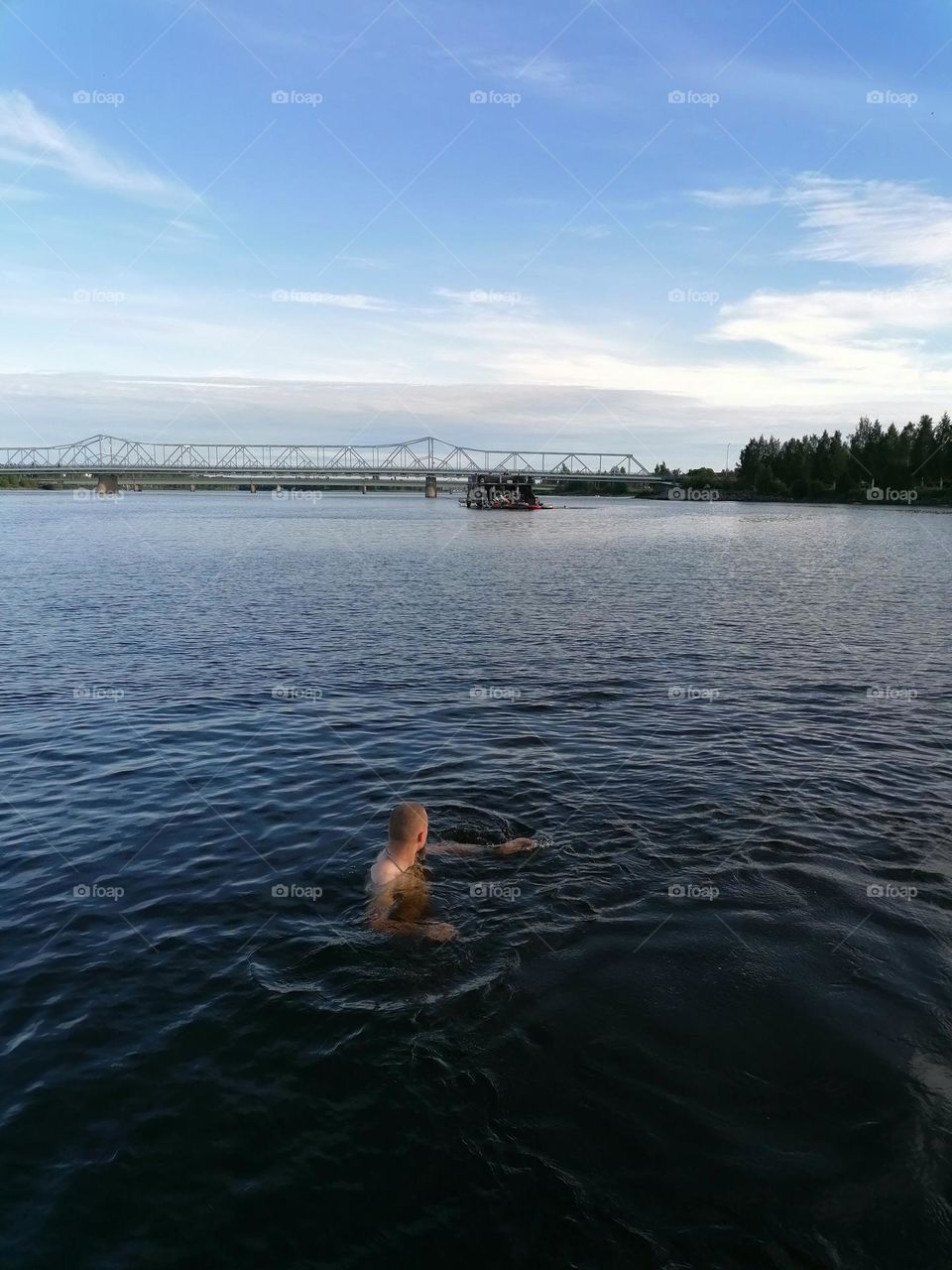 People / a man swimming on a Finnish beach on a warm summer day