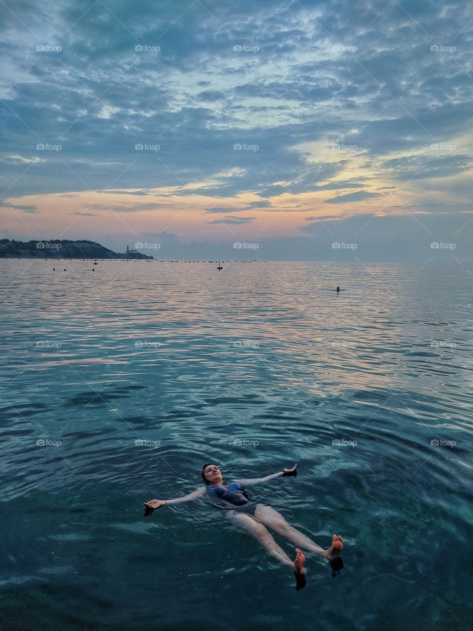 Relaxed girl enjoying her summer vacation at the sea and swimming on her back