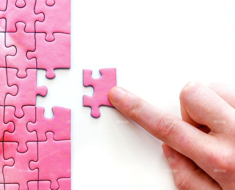 Hand putting last piece in a puzzle