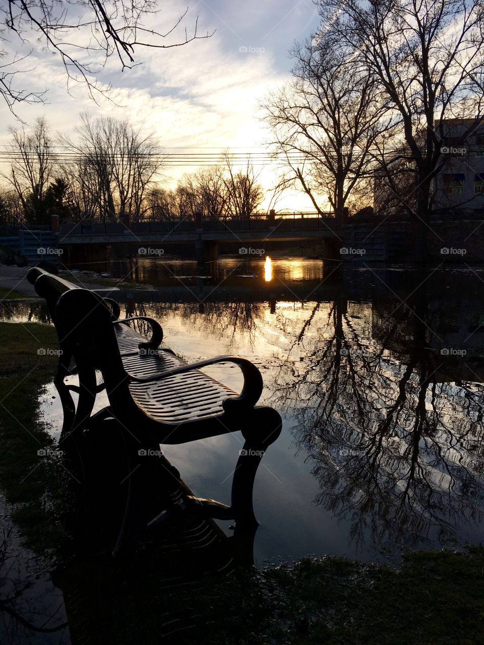 Flooded park bench at sunset