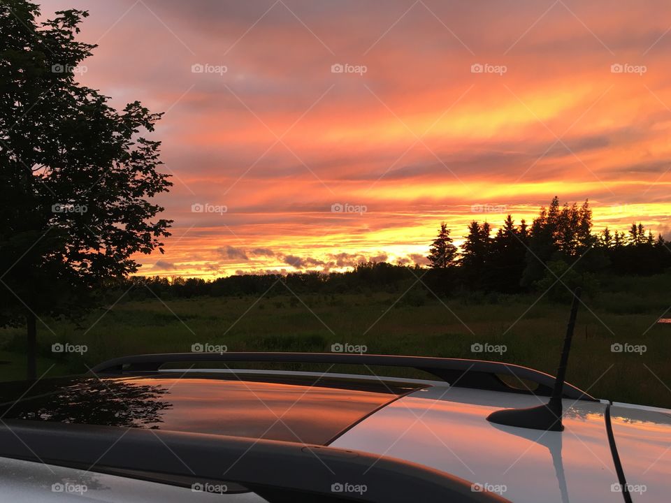 High angle view of reflection of orange sky at sunset on panoramic sunroof of car road trip and adventure travel background 