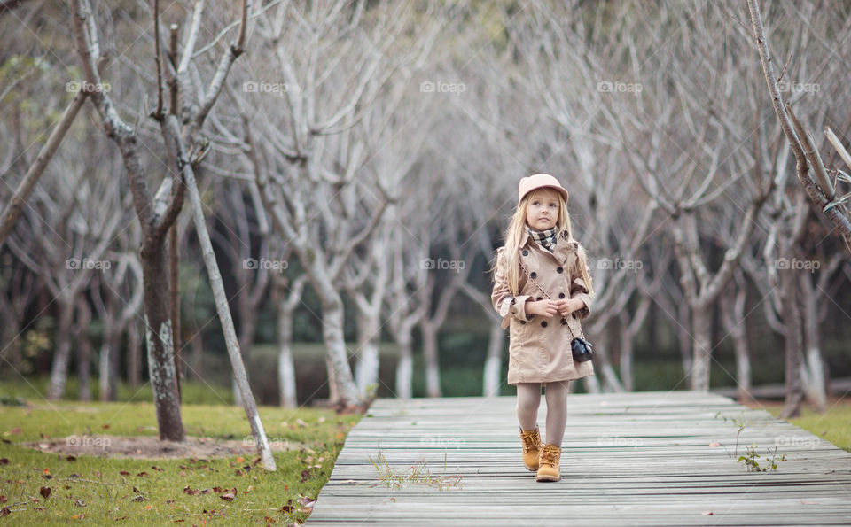 Stylish little girl with blonde hair walking in the park 