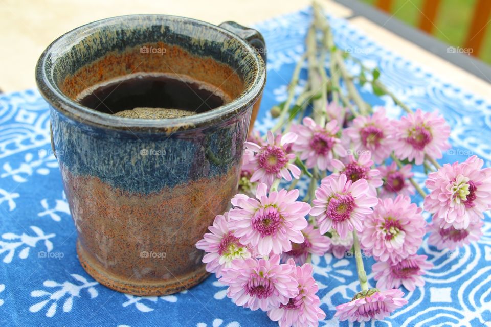 Coffee in a pottery mug and flowers