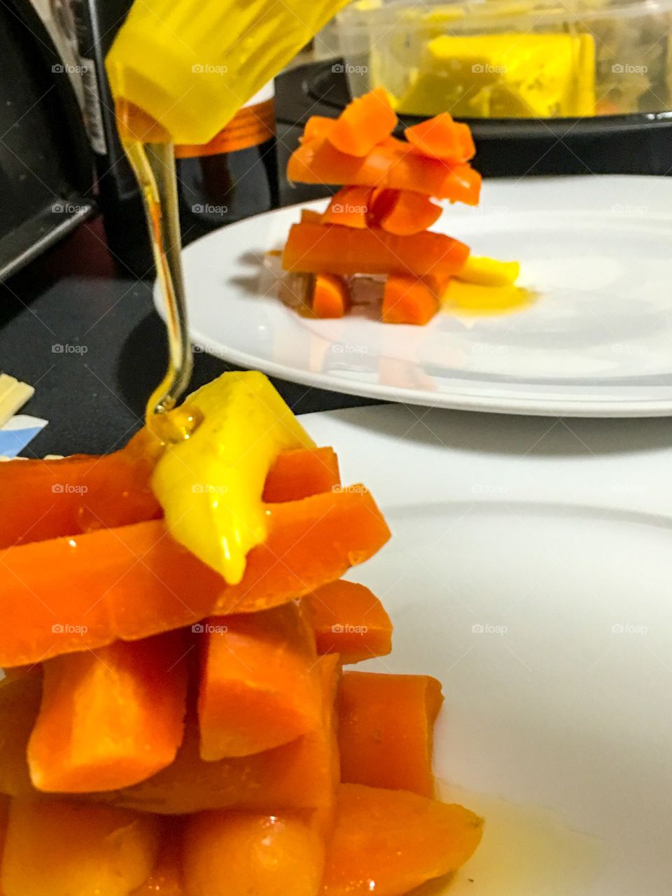 Carrot sticks steamed stacked on plate with honey and butter food presentation