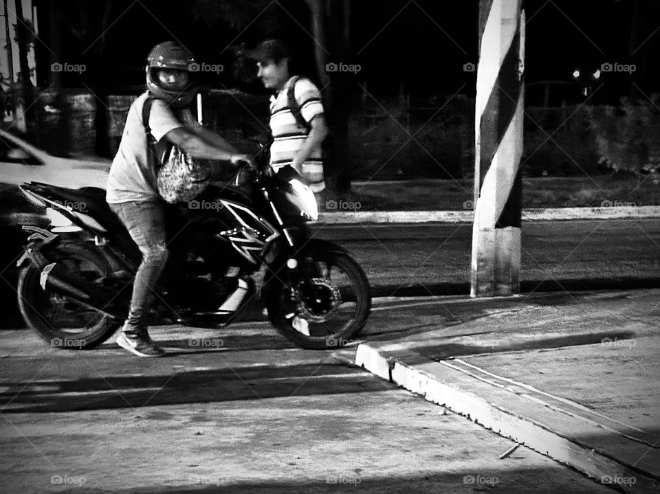 Man giving a ride to a friend in his motorcycle at the midnight, monochrome style.