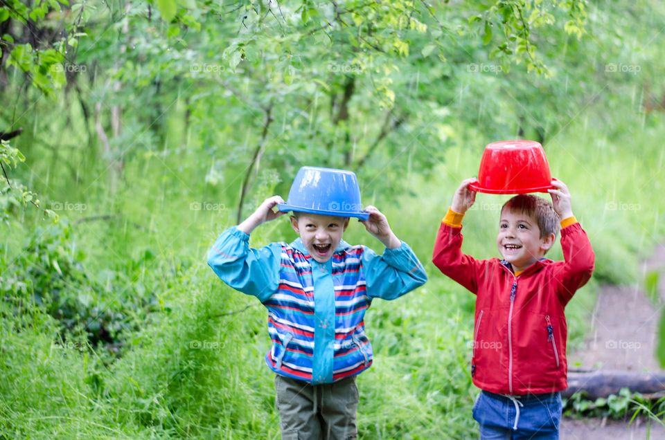 Children Playing in Rainy Spring Day with Buckets on Their Heads