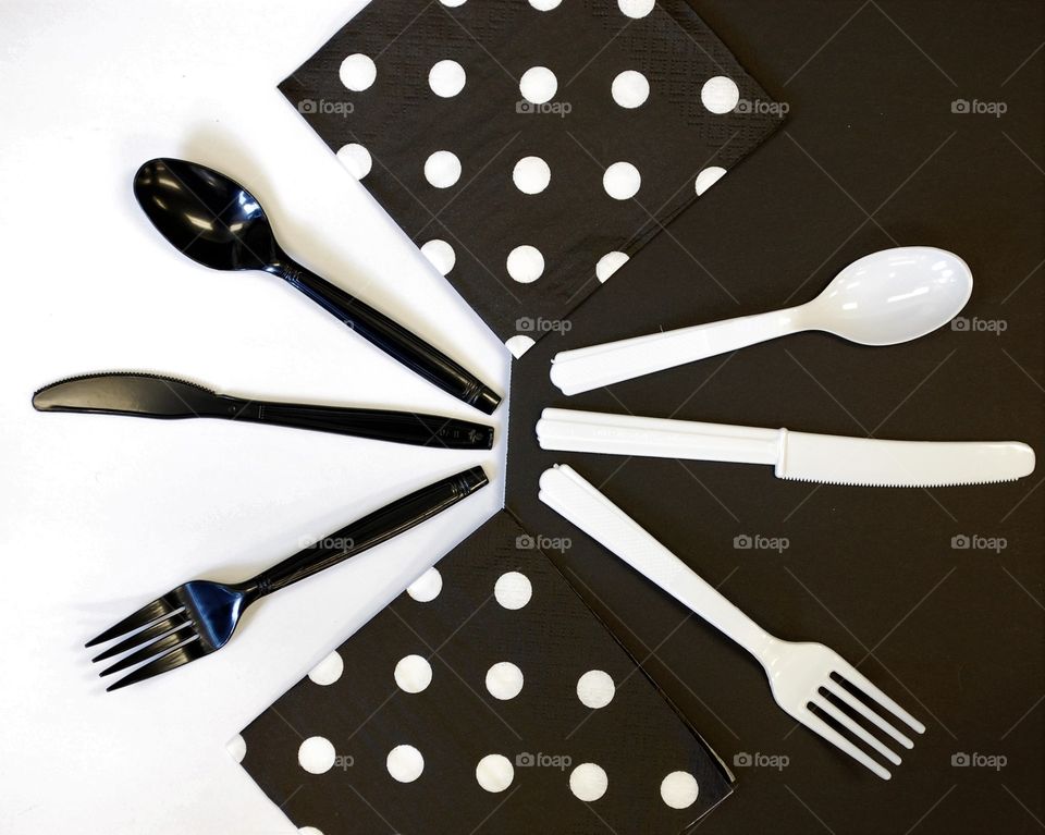 Contemporary Abstract with opposites. Black and white silverware and napkins on a. Lack and white background 