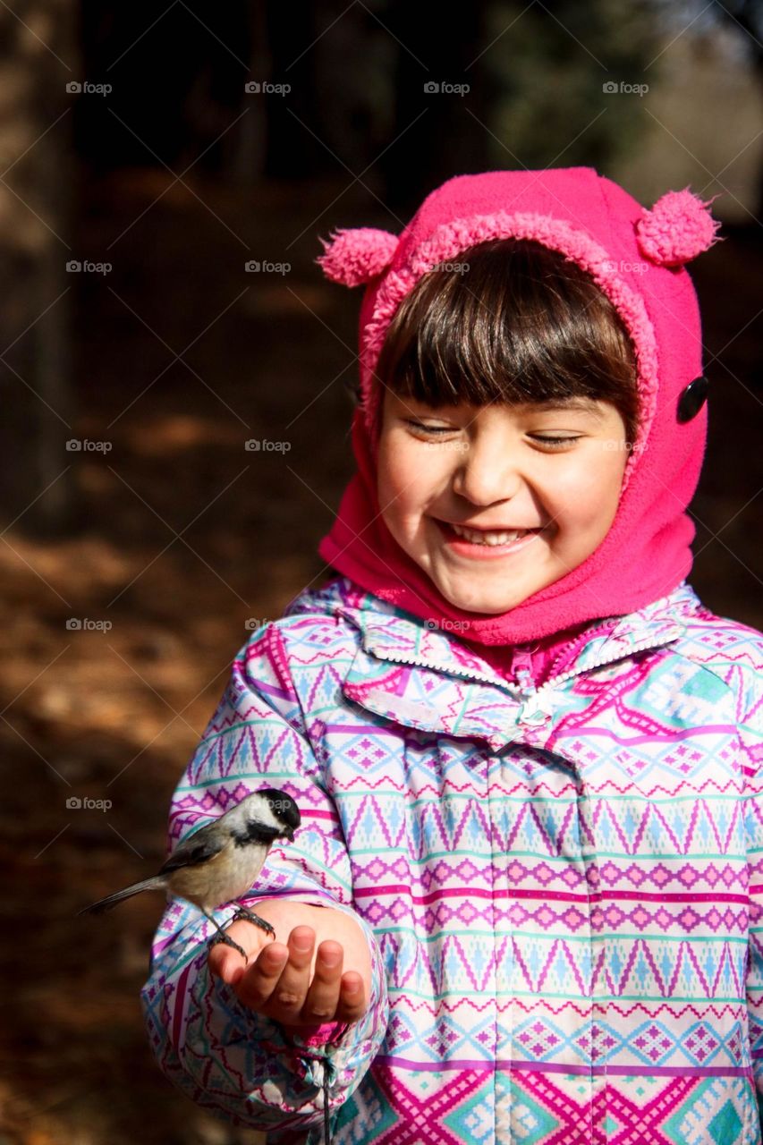 Happy girl is feeding chickadee