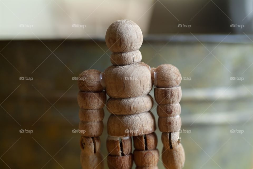 A wooden man used as an artist drawing tool stares into the camera.