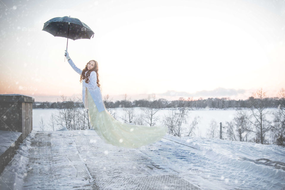 Woman in the air while holding umbrella