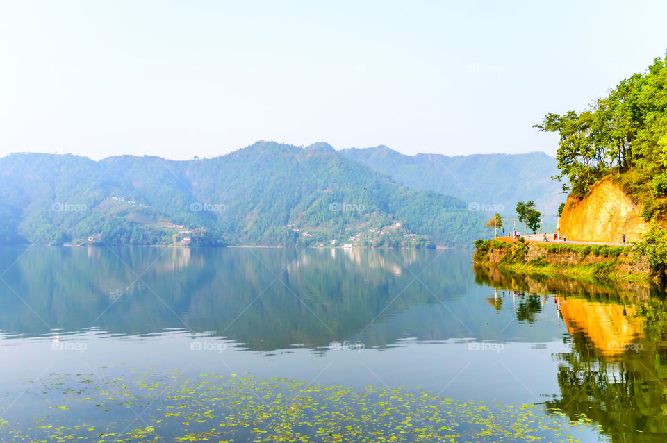 Photograph of autumn colourful lake, mountain, clear sky with reflexation in water. Wide angle landscape of Pokhara Lake at Kathmandu Nepal. Vintage film look. Vacation Freedom, Simplicity Concept.