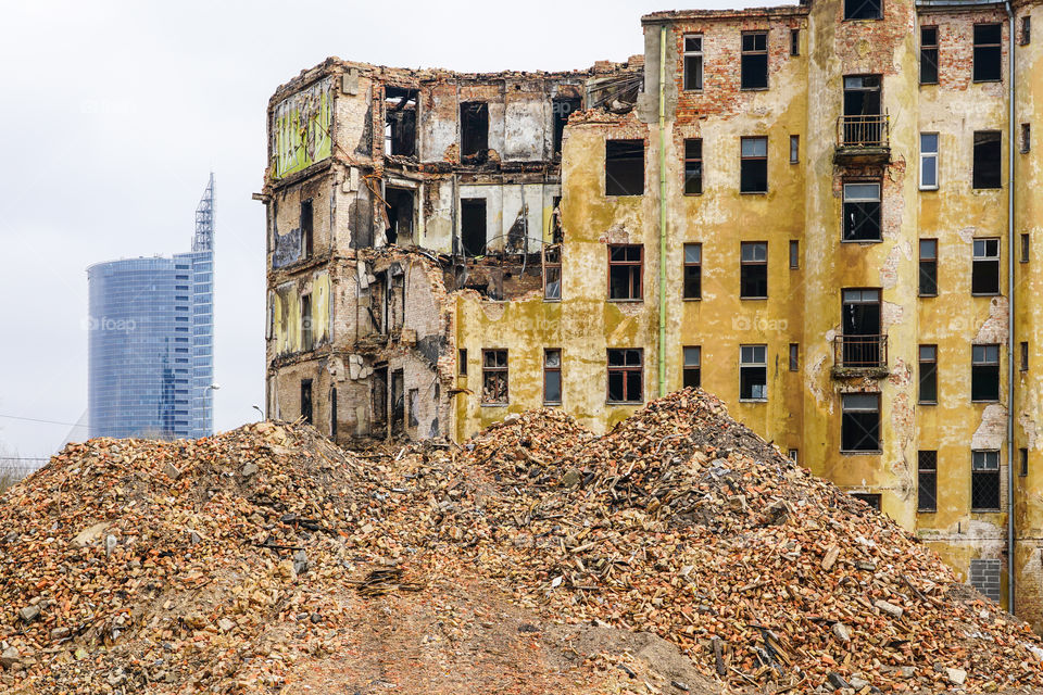 demolition of a large old historic stone house in the city, new multi storey buildings in the background
