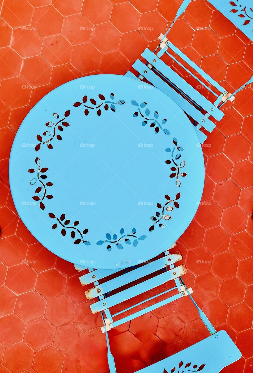 A blue bistro table against an orange tile floor.