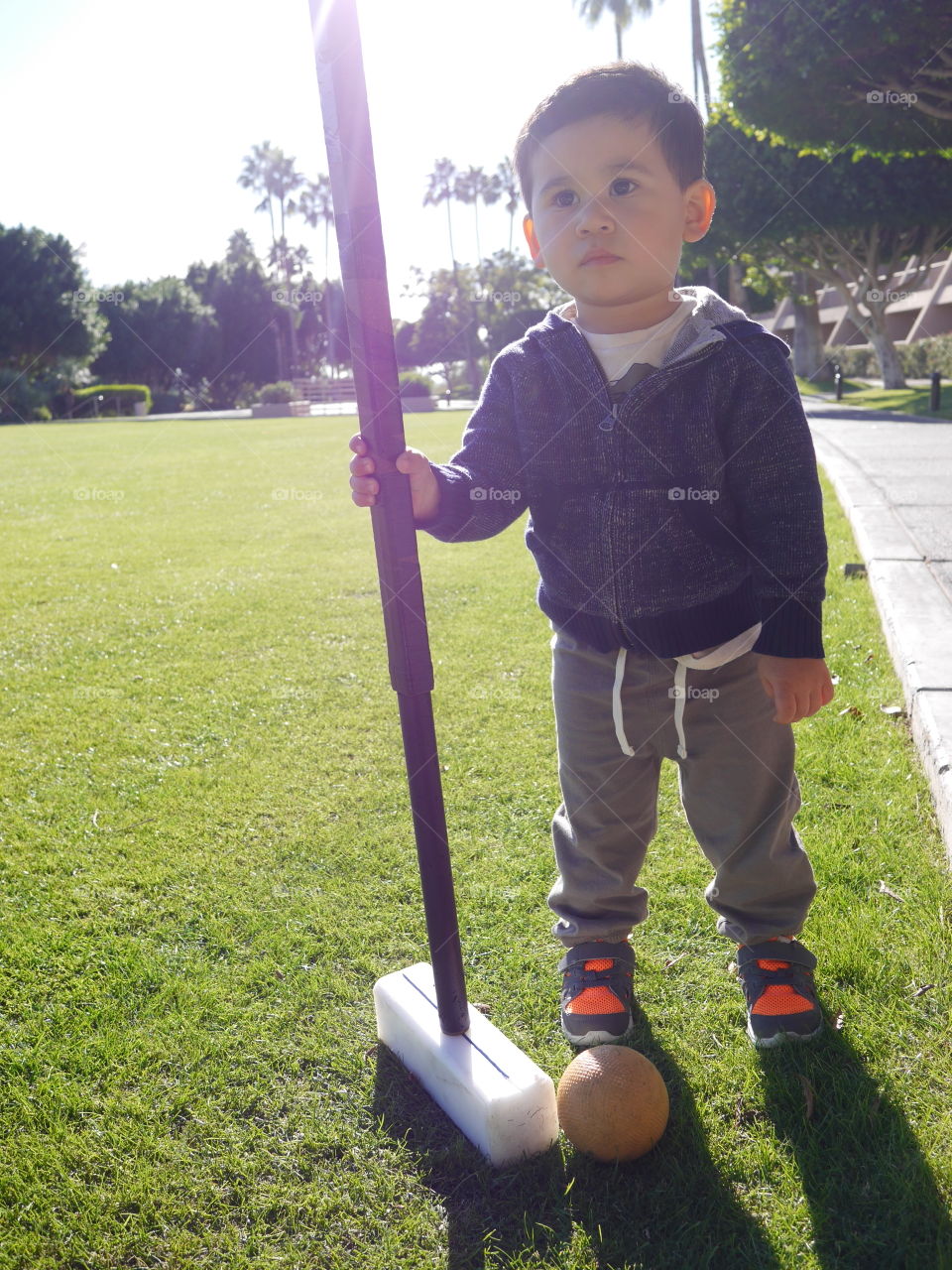 Boy holding big mallet with ball on green grass