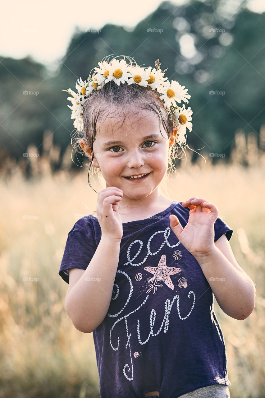 Little girl wearing a coronet of wild flowers on her head. Candid people, real moments, authentic situations