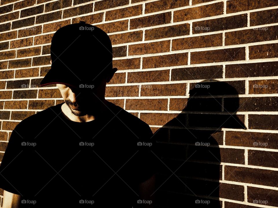 Sadness depicted by the shadow side of a man with his head down .