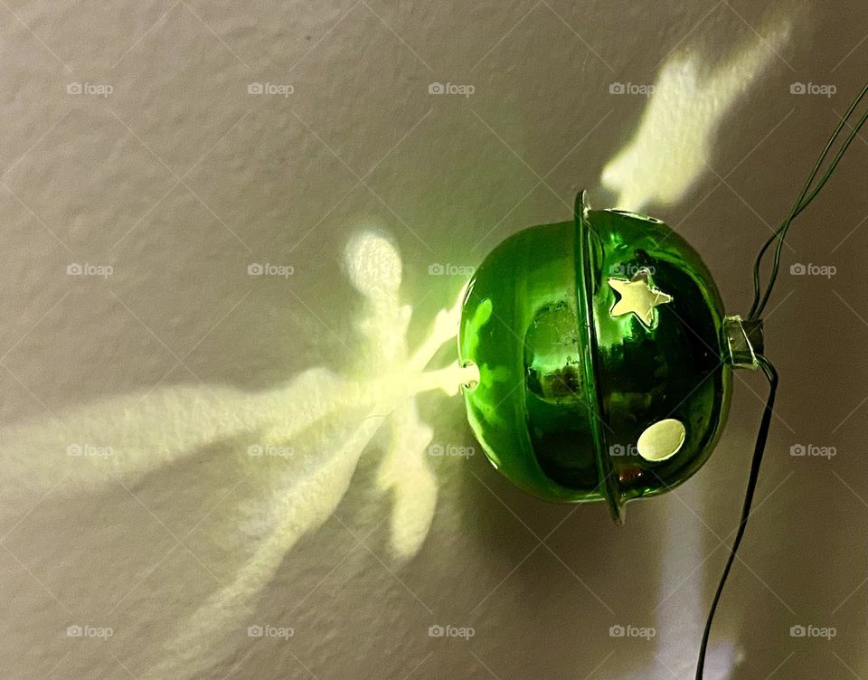 Green Christmas bell light making reflections on a wall