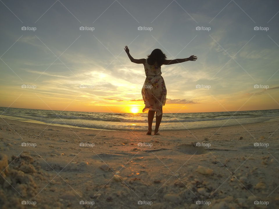 Woman dancing at beach at dusk