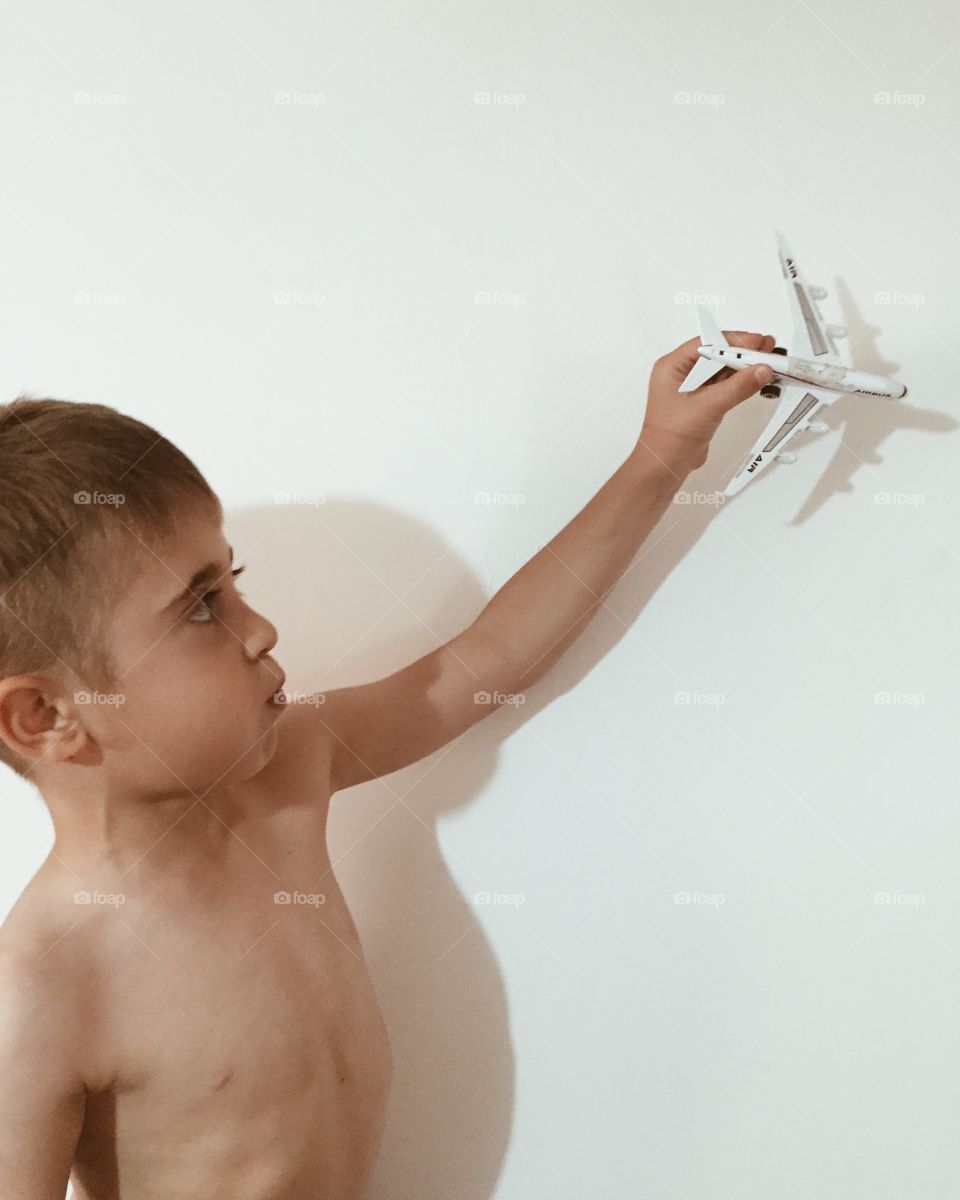A boy playing with airplane toy on white background