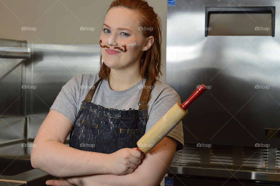Funny redhead young woman Chef baker with messy face and mustache and rolling pin with Apron.