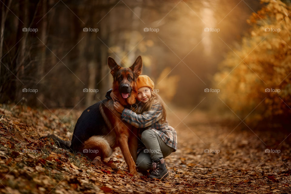 Little girl with dog in autumn park 