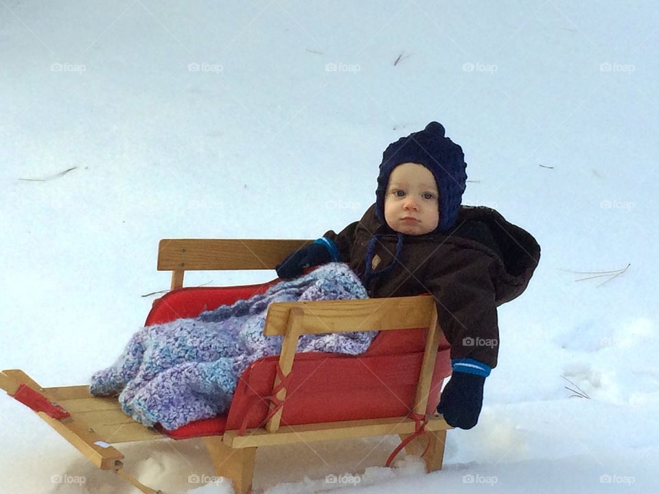 A little toddler on sledge sliding during winter