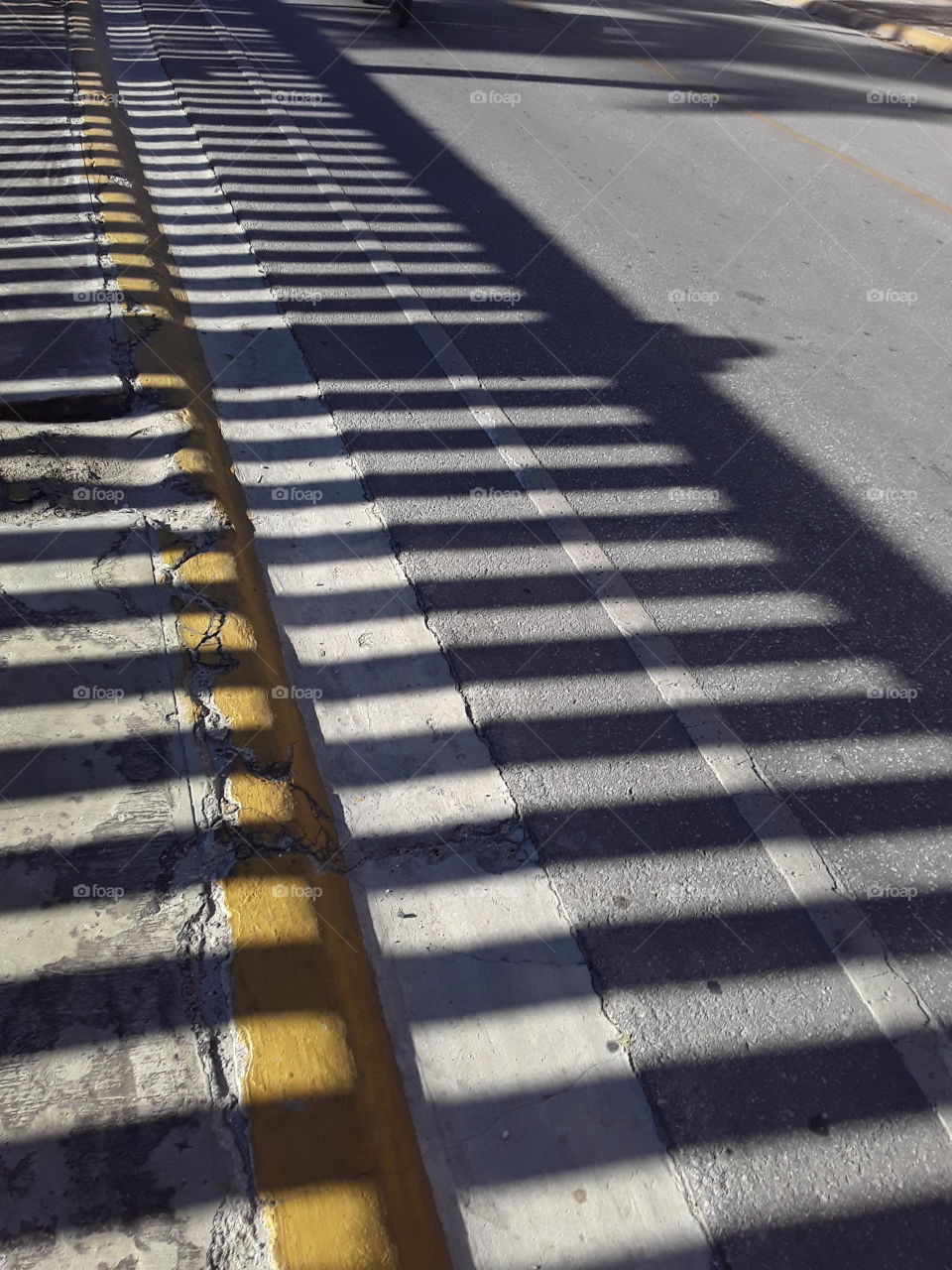 fence shadow on asphalt road