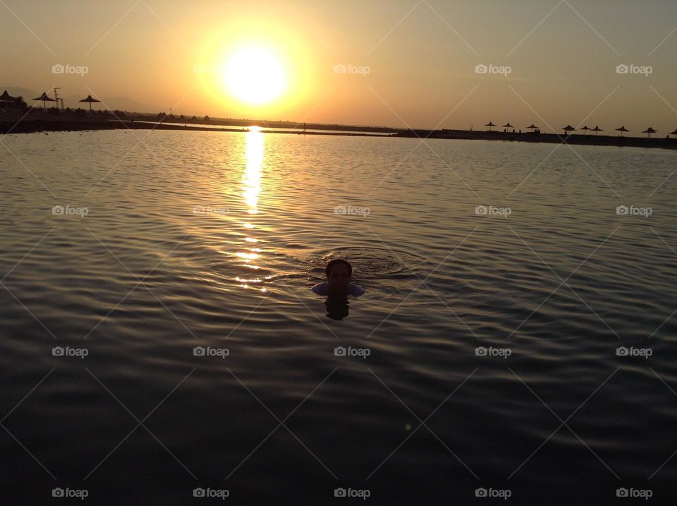A girl swims at the Red Sea before sunset 