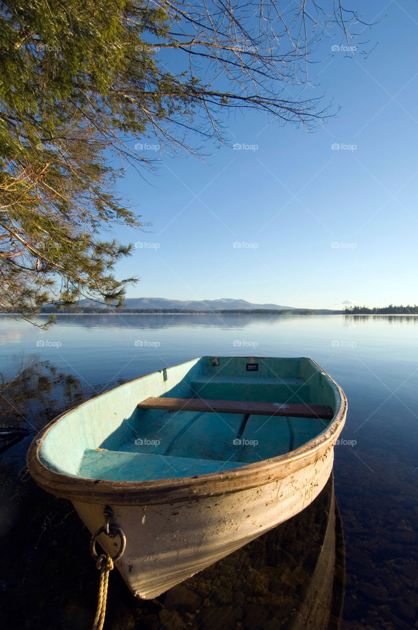 Rowboat sits in the calm water on the shore of lake Winnepesaukee