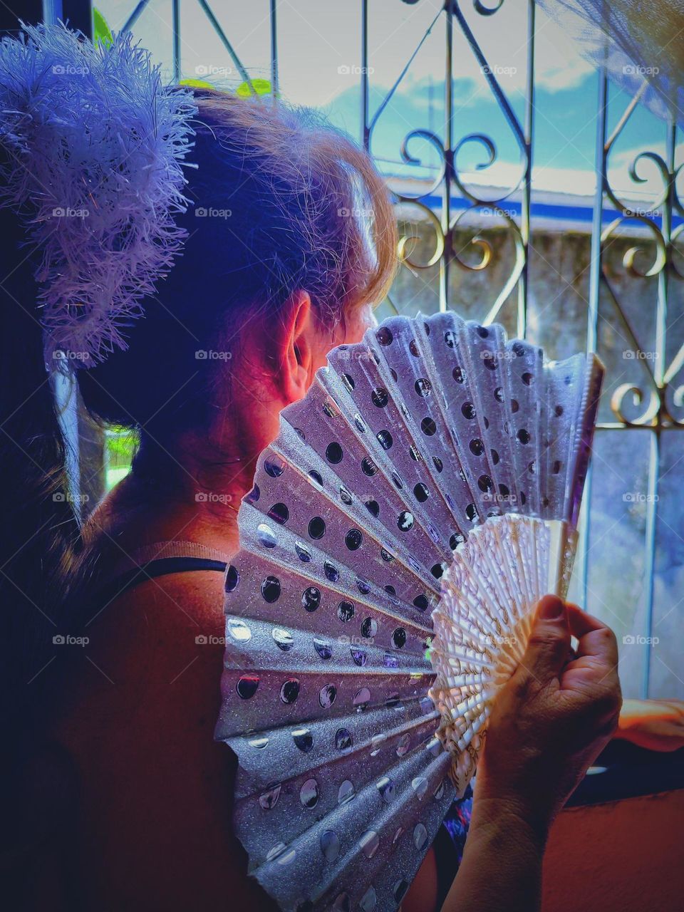 The look of the beautiful girl with her fan through the window.