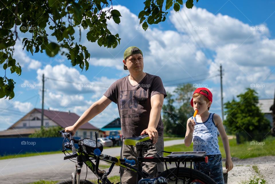 Father and son have fun together, ride bikes in the summer in the countryside, sunny day