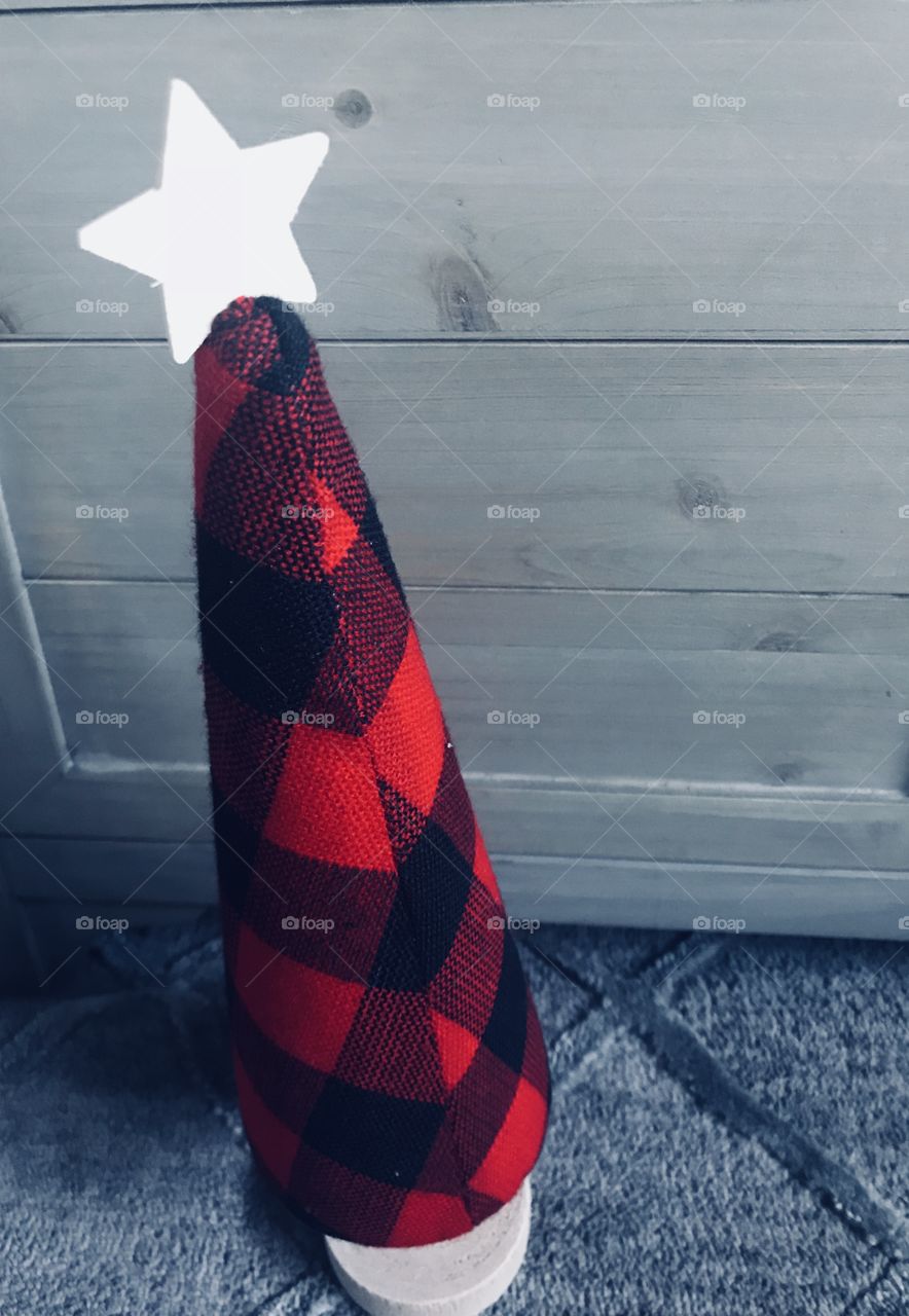 A country plaid red and black checkered Christmas tree with a wooden star on top. 