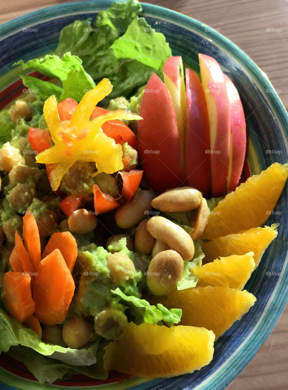 A healthy Vegan salad of lettuce, chick peas, peanuts, carrots, tomato, yellow peppers, orange & apple slices with a garlic lime avocado dressing. Yum!