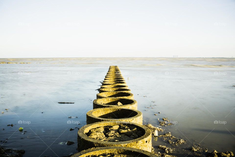 several breakwater stones on the beach which are placed parallel to resemble a bridge in the middle of the sea