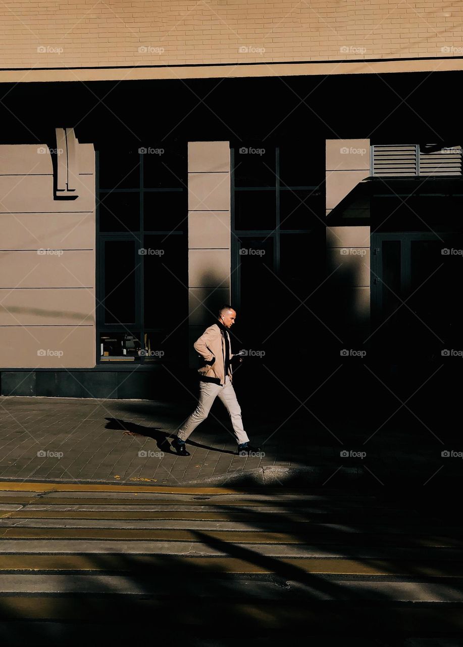 Young stylish male walking on the street in sunny spring day