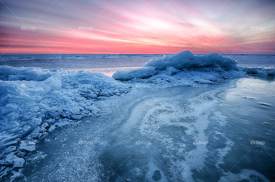 frozen winter sunrise seascape with ice and colorful sky