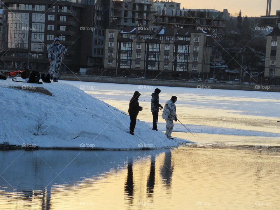 The ice has just melted on the shore, fishermen are trying to catch fish, there is still snow and ice, it’s cold