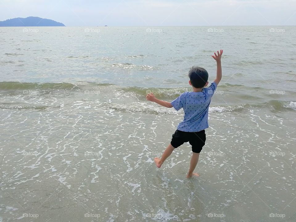 Child playing by water on beach 