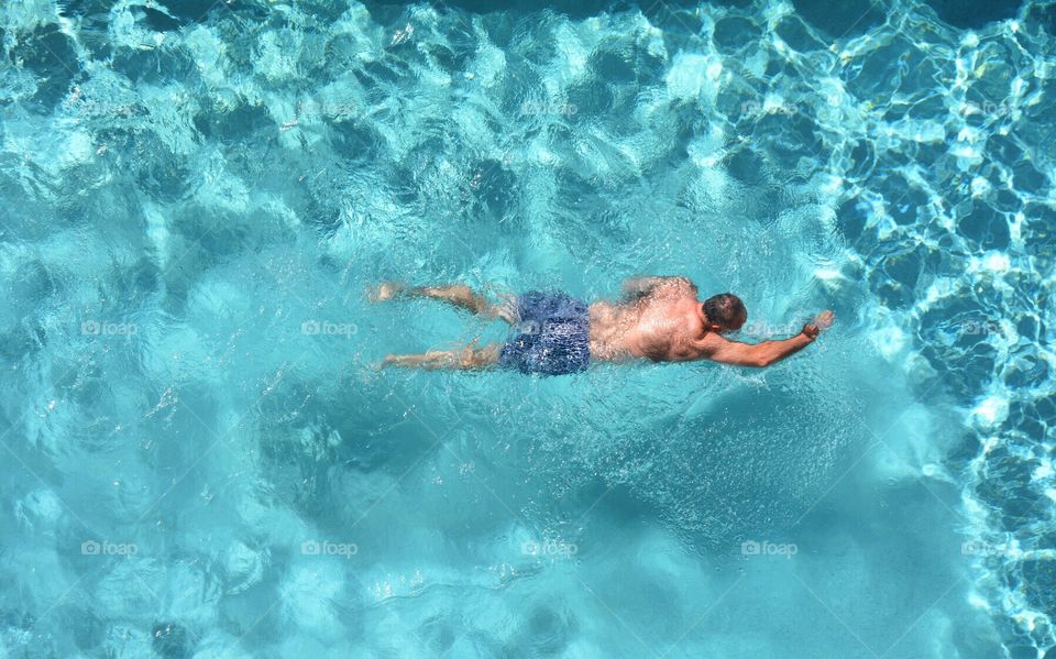 A man swimming laps freestyle stroke to exercise.