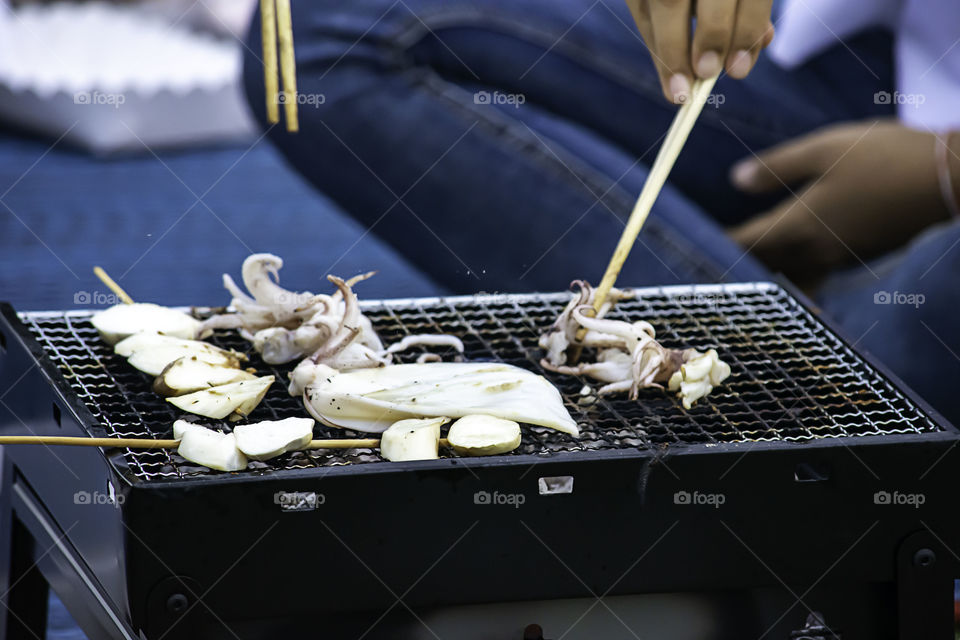 Fresh squid and mushrooms on the grill grate steel.