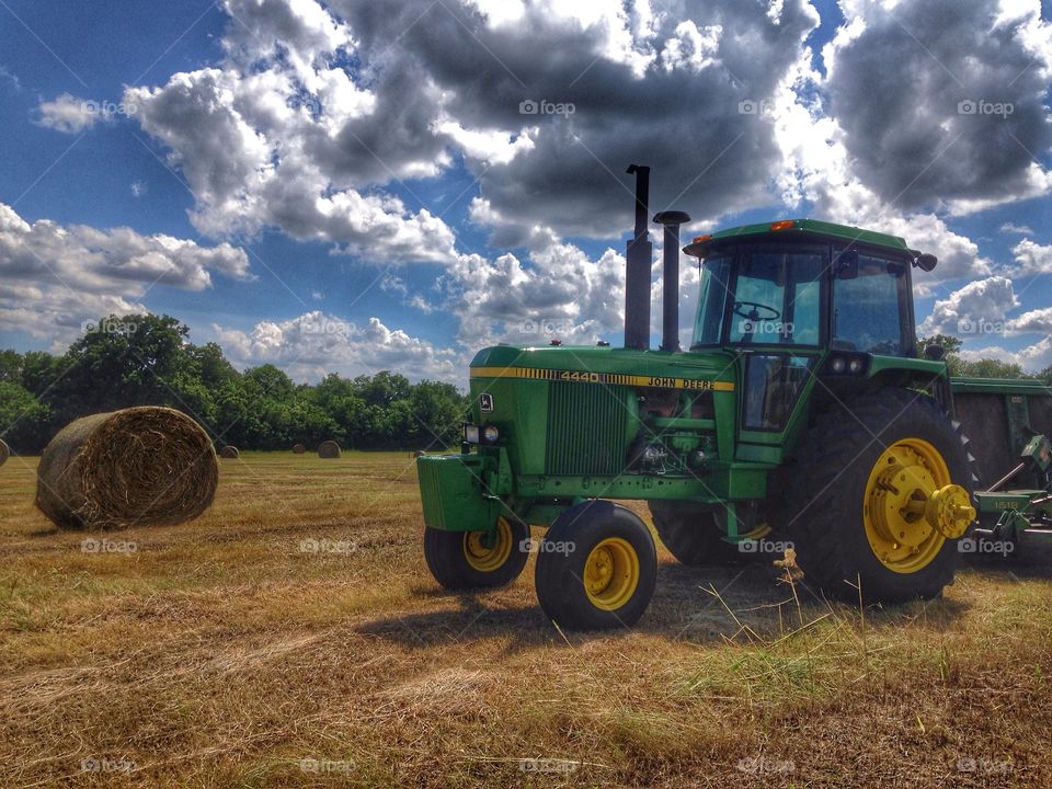 Hay day. John Deere tractor and field of hay