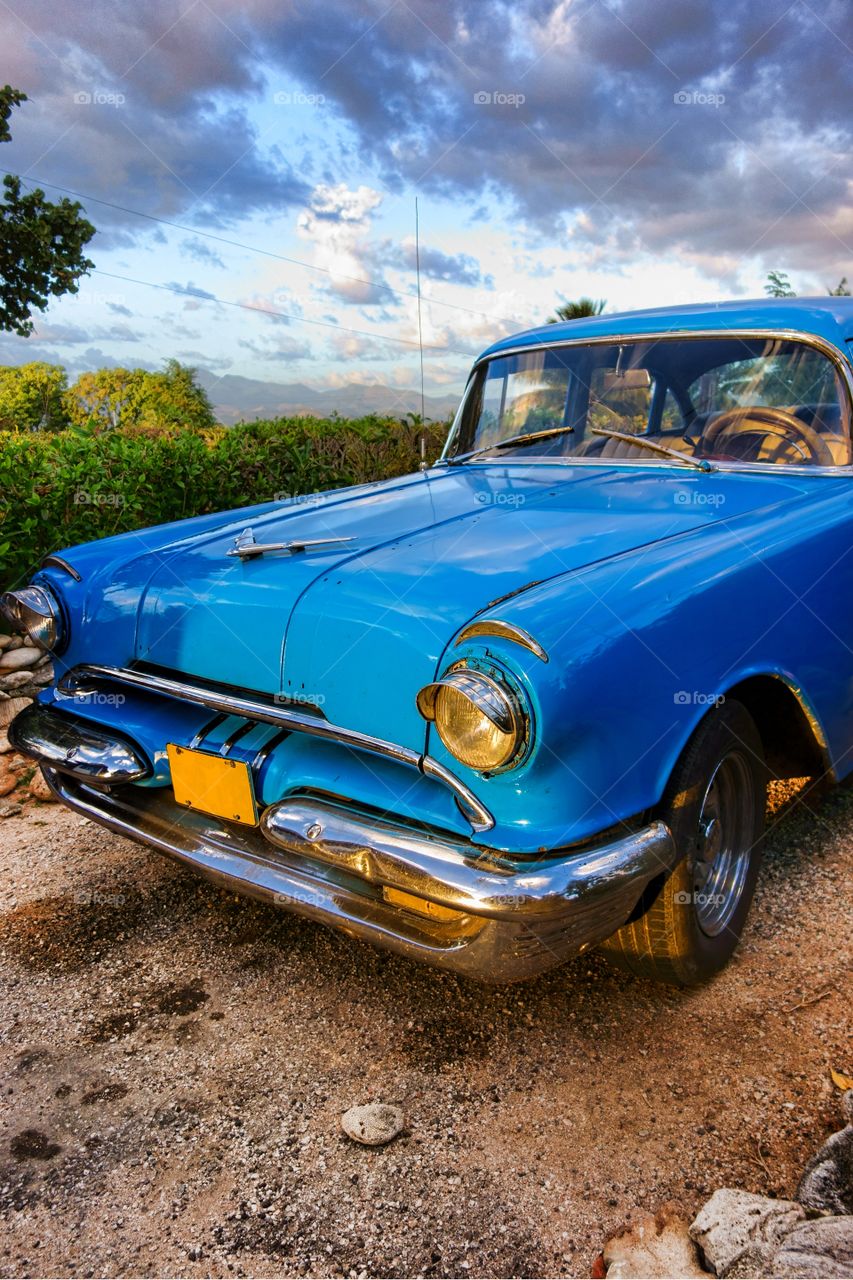 Classic car in Trinidad, Cuba. Old blue American classic car at sunset time in mountainous and green outdoor setting in Trinidad, Cuba.
