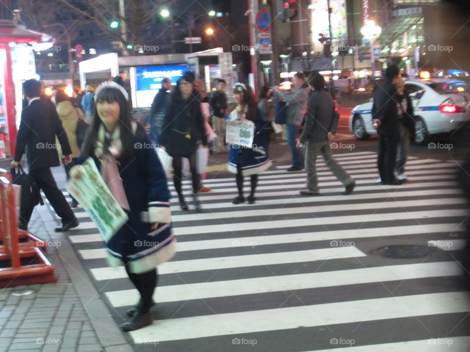 Akihabara, Tokyo, Japan. People and Girls from Maid Cafes in Street at Night.