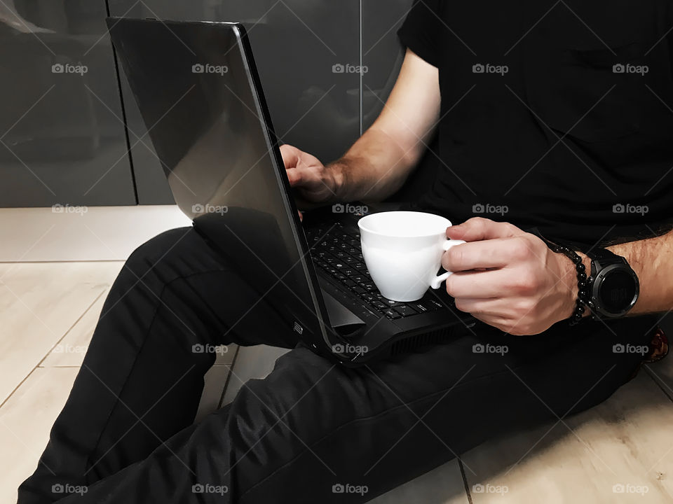 Young man drinking coffee and using his notebook while checking social media in the morning at home 