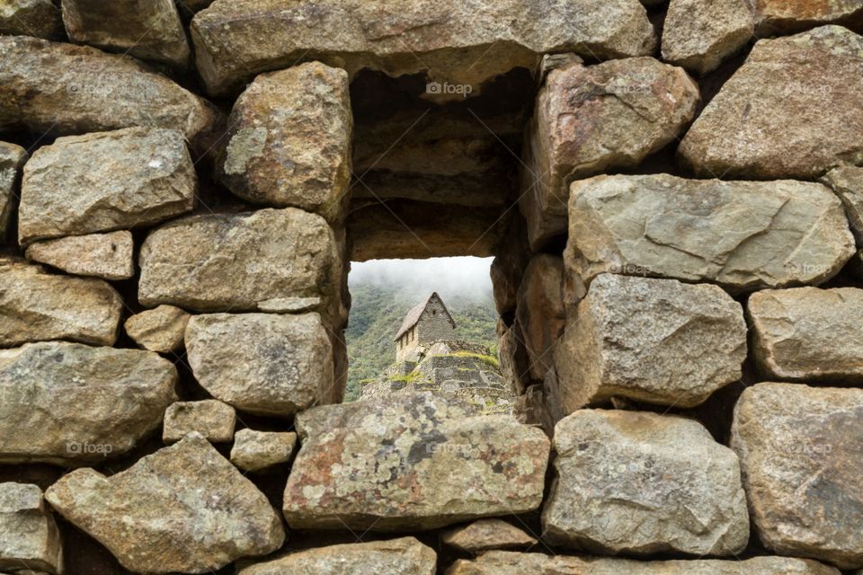 View through stone window. View through stone window at Machu Picchu. Building standing on the top of the hill. Thick rock wall