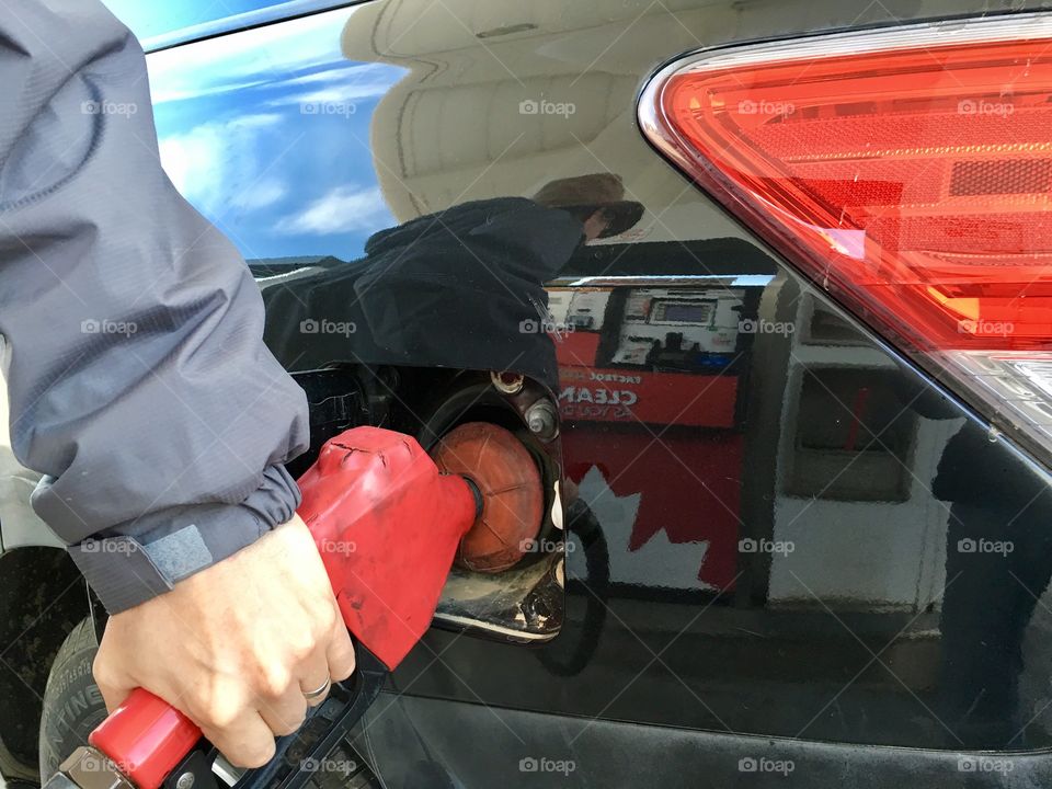 Red gas pump handle, man pumping gas