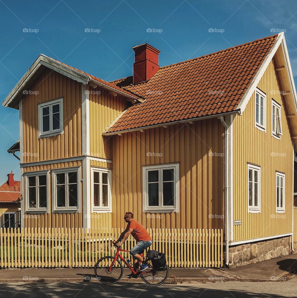 Man riding bicycle in front of house