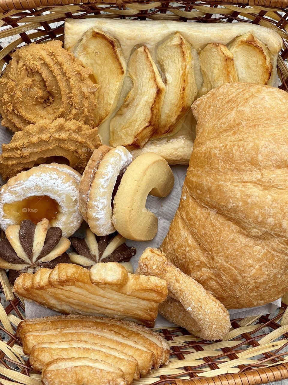 Basket of assorted freshly baked bakery products, cookies, biscuits, bread and croissant seen from above, Italian patisserie 