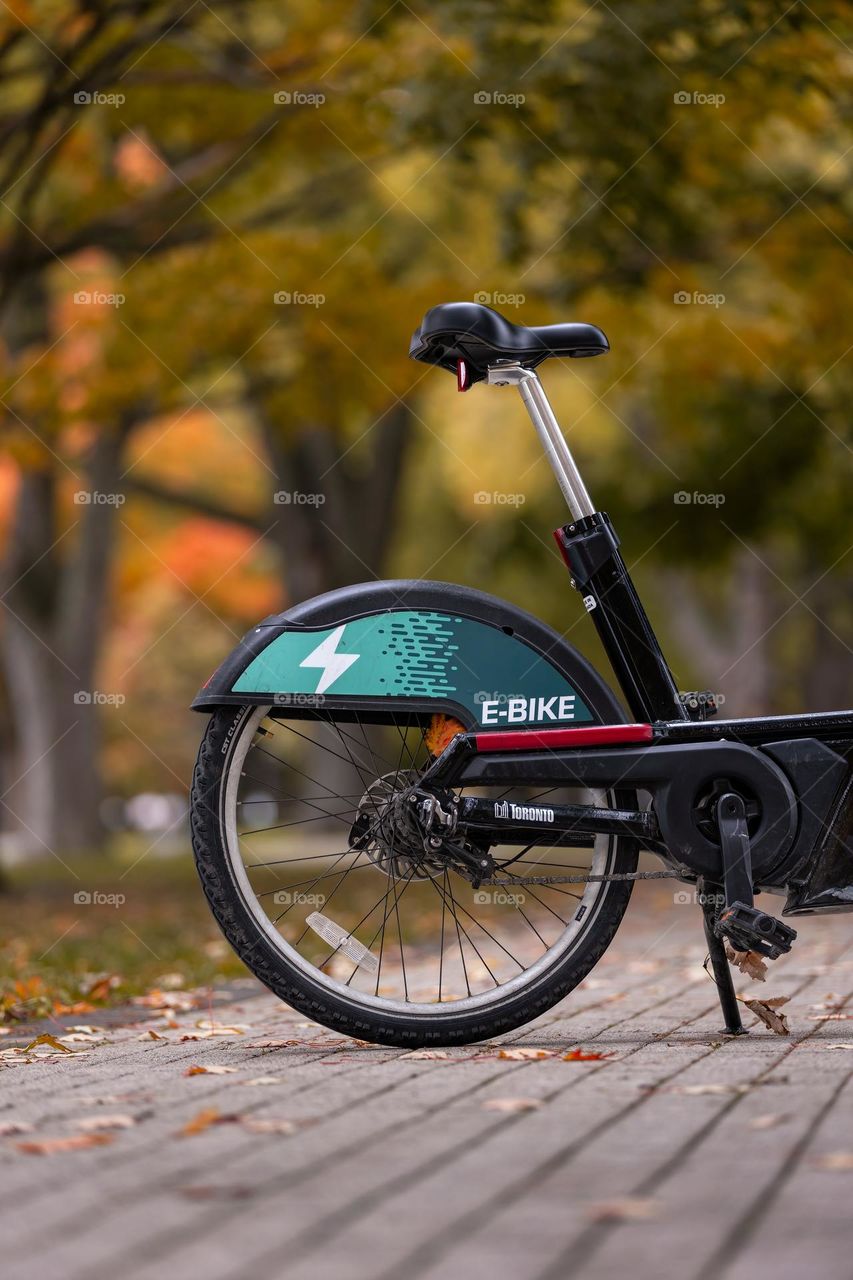 Close up of a lone city bike outside in a park surrounded by colorful fall foliage