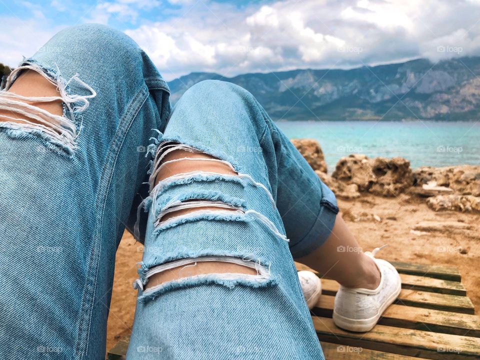 View and legs in jeans resting girl on the beach